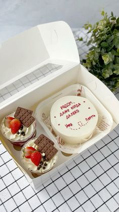 three small cakes in a box with strawberries on top