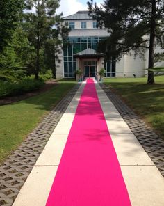 the walkway is painted pink and white in front of a large building with lots of trees