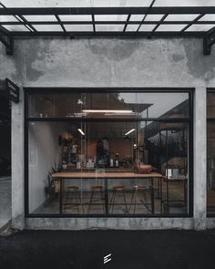 the inside of a restaurant with tables and stools in front of glass doors that are open