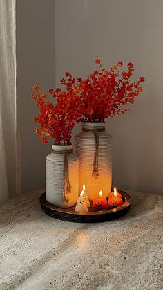 two vases with flowers and candles on a table