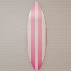 a pink and white surfboard hanging on the wall