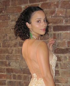 a woman in a dress standing next to a brick wall