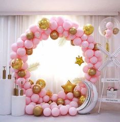 a pink and gold balloon arch with balloons