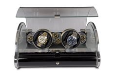 three watches in a glass display case on a white background, with the reflection of another watch