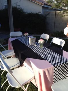 the table is set up with black and white checkered cloths on it for an outdoor party