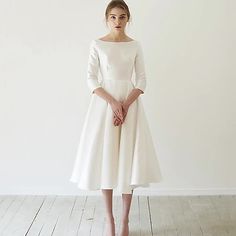 a woman in a white dress standing on a wooden floor