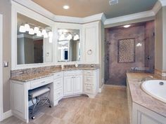 a large bathroom with marble counter tops and white cabinets