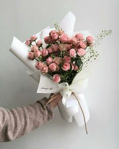 a person holding a bouquet of pink roses