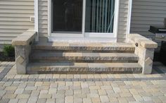 a brick patio with steps leading up to the front door