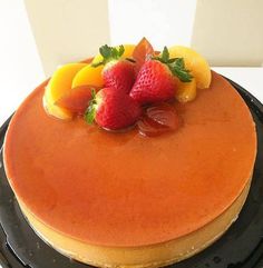 a cake with fruit toppings on top is sitting on a black plate and white background