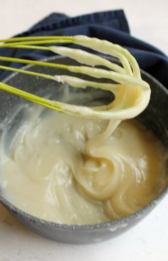 a metal bowl filled with cream and whisk on top of a table next to a blue napkin