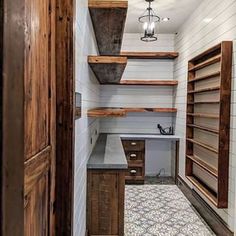 an empty pantry with wooden shelves and shelvings on the wall, next to a tiled floor