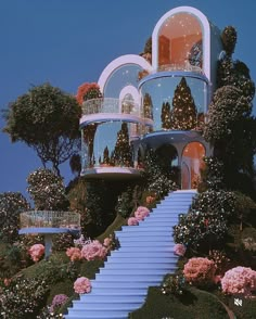 a house on top of a hill with stairs leading up to the upper level and flowers growing all around it