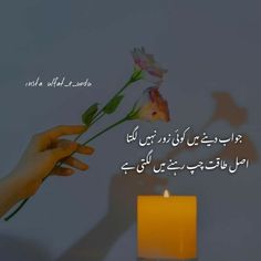 someone is holding a flower in front of a candle with arabic writing on the side