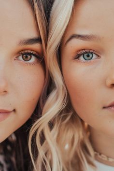 two beautiful young women with blue eyes posing for the camera, both wearing necklaces