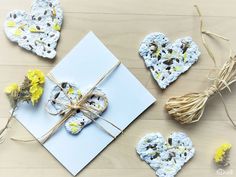 two hearts shaped cookies are tied to a white envelope with twine and flowers on the table