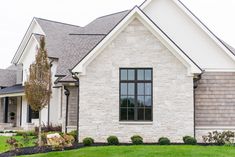 a house that has some grass in front of it and bushes on the lawn behind it