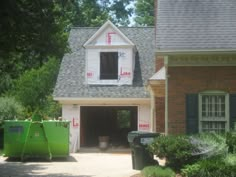 a house under construction with trash cans in front