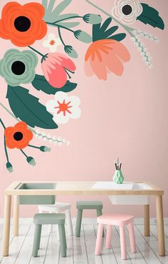 a dining room with pink walls and floral wall decals on the wall, along with a wooden table