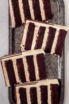 three slices of chocolate cake with white frosting on a metal tray next to each other