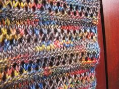 a close up view of a multicolored crocheted bag hanging on a wooden door