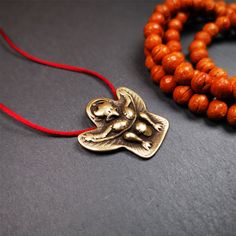 two wooden beads and an elephant pendant on a red string