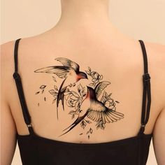 the back of a woman's shoulder with a bird and flowers tattoo on it