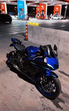 a blue motorcycle parked in front of a gas station with no one on it's bike