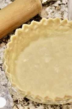 an uncooked pie crust sitting on top of a counter next to a rolling pin