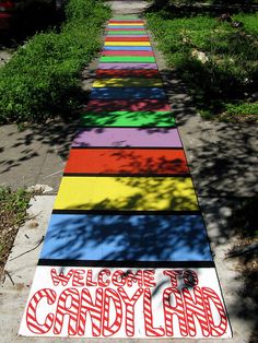 there is a rainbow painted path that says welcome to candy land