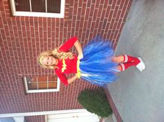 a woman in a red shirt and blue tutu skirt is posing for the camera