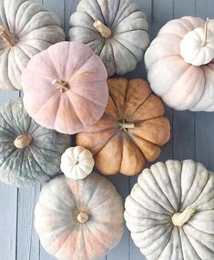 pumpkins are arranged on a wooden surface with white and gray ones in the middle