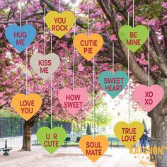 hearts hanging from the branches of trees with words written on them in different colors and shapes