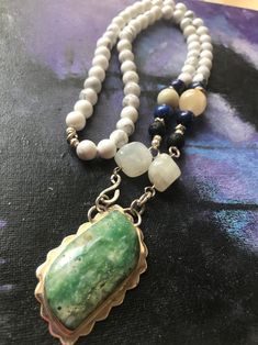 A chunky bohemian necklace with a large green raw jasper pendant encased in heavy sterling silver framework with multi gemstones beads. Handmade unique statement necklace with genuine white Howlite beads , natural blue Lapis lazuli, raw black Lava, a few Agate, and Moonstone crystals. Measurements- jasper pendant- 53 mm x 30 mm Necklace-25 inch wearable length Gemstone beads - 8 mm The Jasper pendant comes with an open back setting to allow its healing energies to the wearer. The necklace closes White Gemstone Necklace, Long Necklace Handmade, Unique Statement Necklace, Green Jasper, Blue Lapis Lazuli, Rare Crystal, Moonstone Crystal, White Howlite, Bohemian Necklace