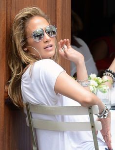 a woman sitting in a chair listening to music on her headphones and wearing sunglasses