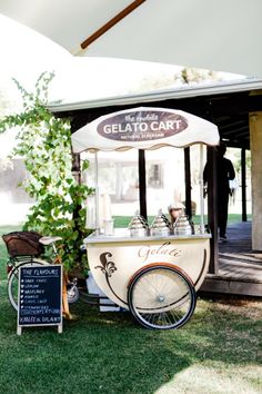 an old fashioned ice cream cart is parked in the grass near a sign that says gelato cart