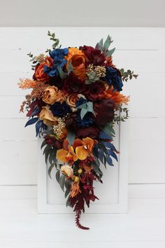 an arrangement of flowers and foliage on a white doorknob with wood planks