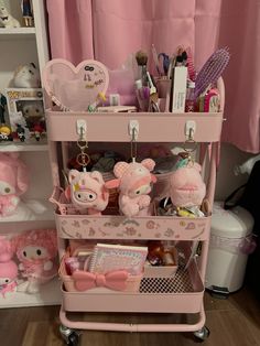 a pink cart filled with lots of toys and stuff in front of a pink curtain