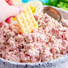 a person dipping crackers into a bowl of tuna salad