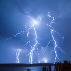 lightning strikes over the ocean and trees