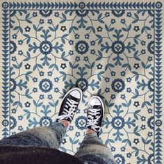 the feet of a person standing in front of a blue and white rug