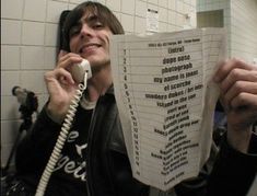 a man is talking on the phone while holding up a stack of paper with words