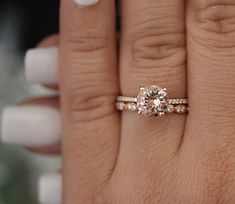 a woman's hand holding a diamond ring on top of her finger and the other hand