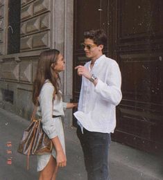 a man standing next to a woman in front of a building