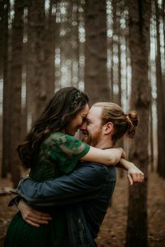 a man and woman hugging in the woods