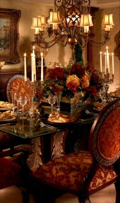 a fancy dining room with candles and flowers on the table, chandelier in the background