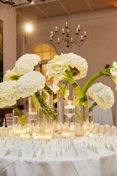 white flowers and candles are arranged in vases on a table at a wedding reception