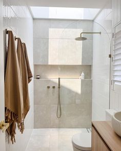 a bathroom with a toilet, sink and shower in it's stall area that has towels hanging on the wall