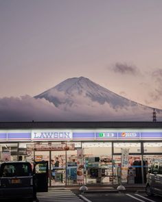 a building with cars parked in front of it and a snow covered mountain in the background