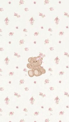 a small teddy bear sitting on top of a white wallpaper covered in pink flowers